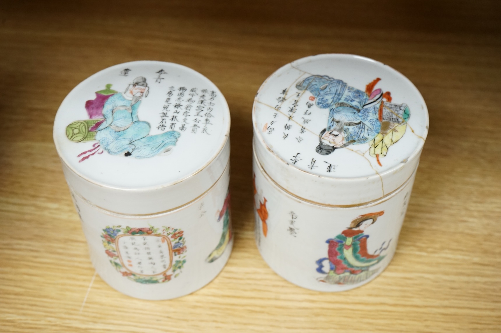 Two mid-19th century Chinese famille rose cylindrical jars and covers, enamelled with figures and calligraphy, 12cm high